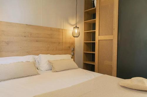 a bedroom with a white bed with a wooden headboard at Sènia Botànic Bonavista in Calella