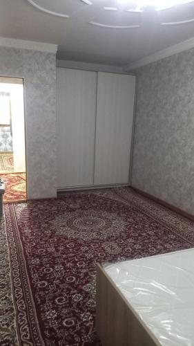 an empty room with a bed and a red carpet at UYUT INN apartment in Samarkand