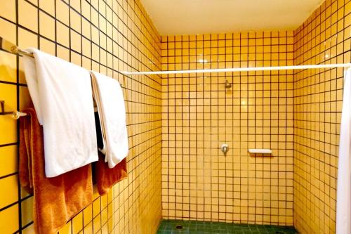 a yellow tiled bathroom with a shower and towels at Phuket Kata Resotel in Kata Beach
