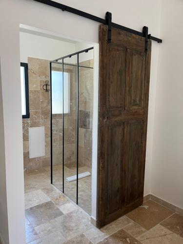 a bathroom with a shower with a wooden door at Les maisons de loup a loup in Cotignac