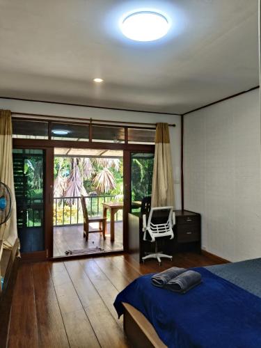 a bedroom with a bed and a chair and a balcony at Lake view house in Ko Phangan