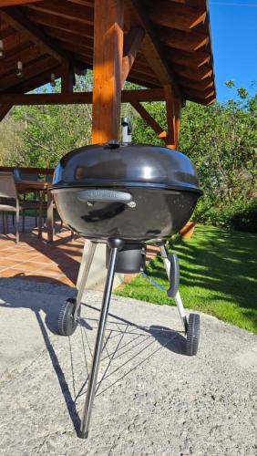 a charcoal grill sitting on a stand under a porch at La Casonia in Anero