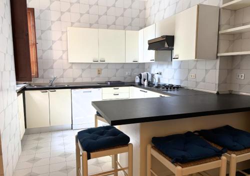 a kitchen with white cabinets and a black counter top at Villa Krizia - Ancona, meravigliosa villa con piscina vista mare in Ancona
