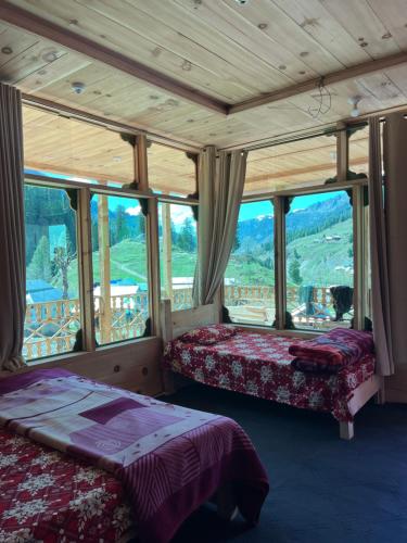 two beds in a room with a large window at Peak Paradise Resort in Taobat