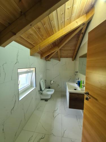 a bathroom with a toilet and a sink and a window at Guest House Korabi in Ceren