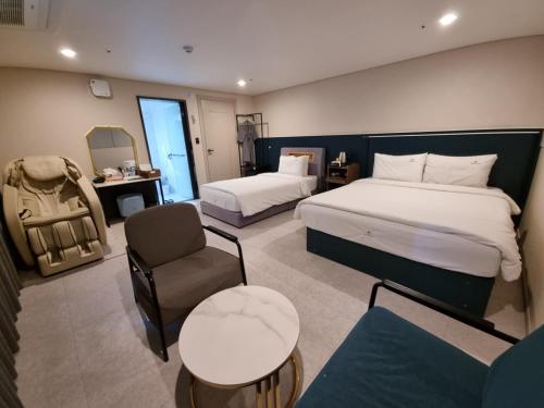 a hotel room with two beds and a chair at Cherryblossom in Changwon