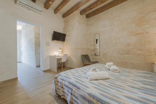 a bedroom with a bed with towels and a desk at Cave Garden rooms in Favignana