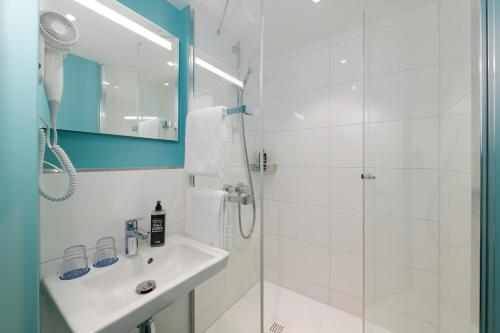 a white bathroom with a sink and a shower at Ibis Budget Leipzig City in Leipzig