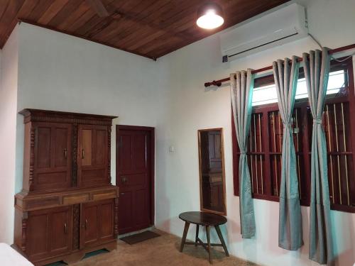 a bedroom with a bed and a wooden cabinet and a table at Karisal Resort & Park in Jaffna