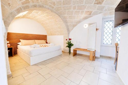 a bedroom with a white bed and a brick wall at Palazzo Kapece in Monopoli