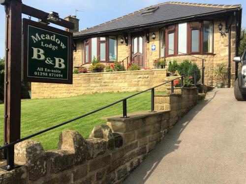 a sign in front of a brick house at Meadow Lodge in Tideswell