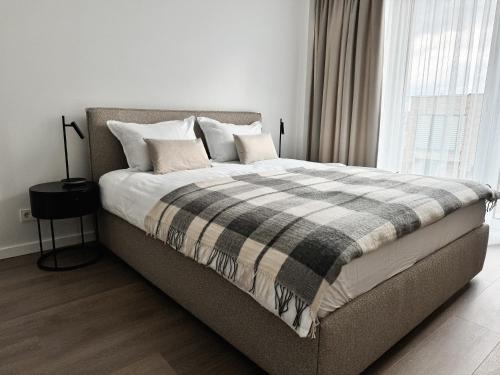 a bed with a plaid blanket on it in a bedroom at Jaukus loftas Šventoji in Šventoji