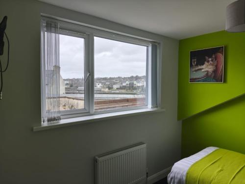 a bedroom with green walls and a window at The Roost in Derry Londonderry