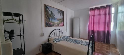 a bedroom with a bed and a window with pink curtains at Résidence Aiko CÔTIERS in Mahébourg