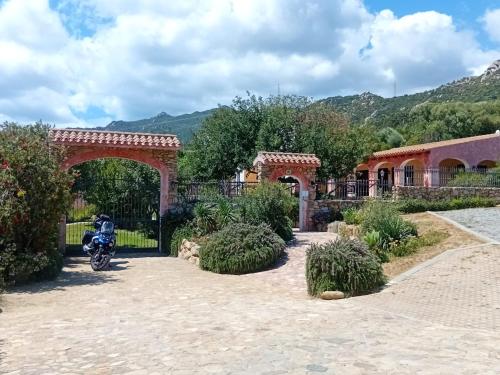a motorcycle parked under an arch in a garden at Hotel La Corte Rosada in Villasimius