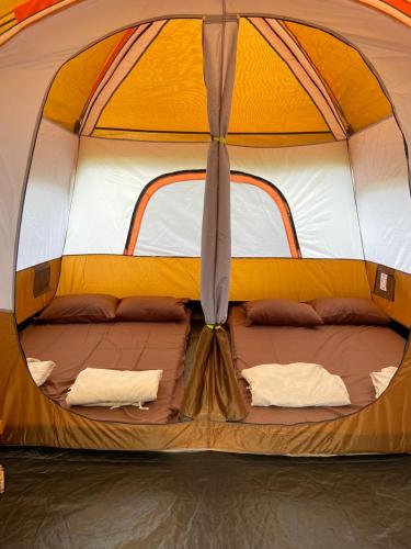 an orange and white tent with two beds in it at Pakis Camping Cikole in Tangkubanperahu