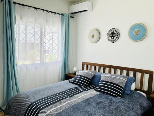 a bedroom with a bed with pillows and a window at Villa Almadies in Pointe-Noire