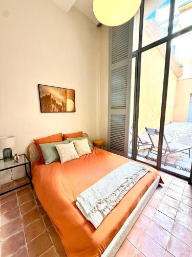 a bedroom with an orange bed and a large window at T2 monument historique Aix en provence in Aix-en-Provence