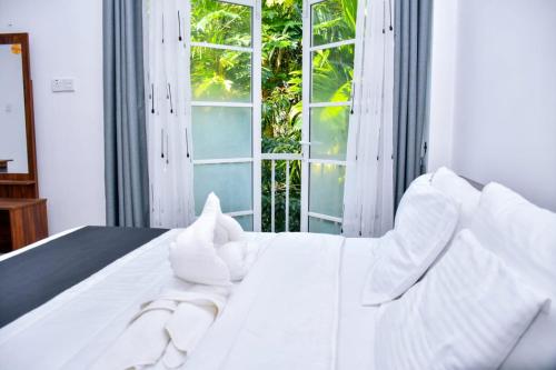a white bed with white pillows and a window at Eco Bless Inn in Kandy