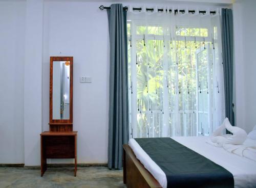 a bedroom with a bed and a mirror and a window at Eco Bless Inn in Kandy