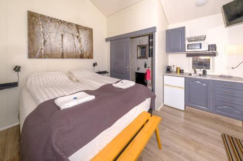 a bedroom with a large bed and a kitchen at Ofanleiti Cottages in Vestmannaeyjar
