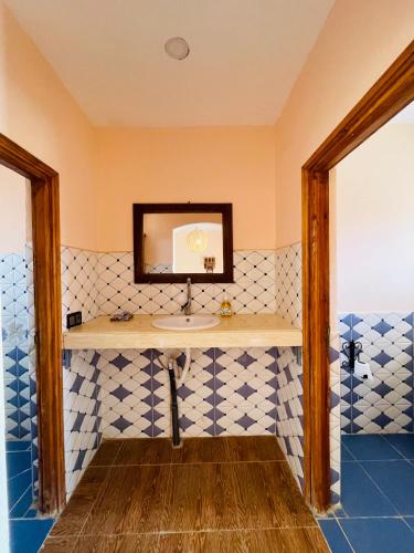 a bathroom with a sink and blue and white tiles at Merzouga Hotel Activities in Merzouga