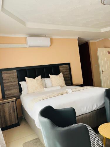 a bedroom with a large bed and a chair at Aurum Stays in Gaborone