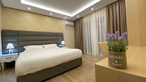 a bedroom with a bed and a vase with purple flowers at Luna Rooms in Golem