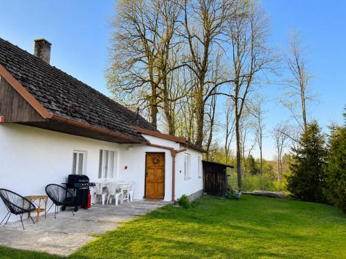 a white house with a table and chairs in the yard at Chaloupka na Perkách in Zahrádky