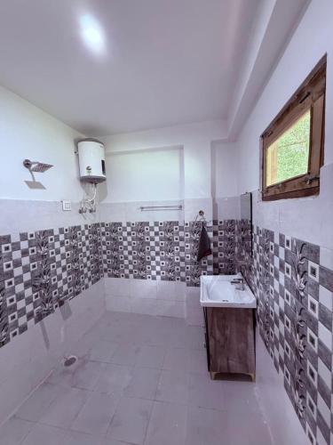 a bathroom with a shower with a sink and a window at Sparrow Whisper in Jibhi