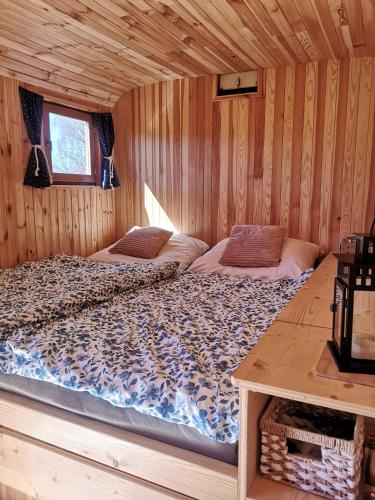 a bedroom with two beds in a wooden cabin at Maringotka Rozálka in Dlouhá Stropnice