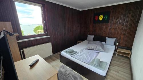 a small bedroom with a bed and a window at Casa Pescărușul Vesel in Baziaş
