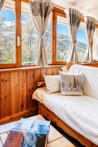 a bedroom with windows and a bed with a table at Petit Chalet Pila in Pila