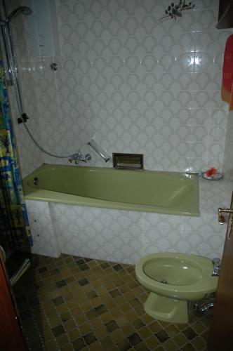 a bathroom with a green tub and a toilet at Panoramablick 85 m2 5 persoons in Lennestadt