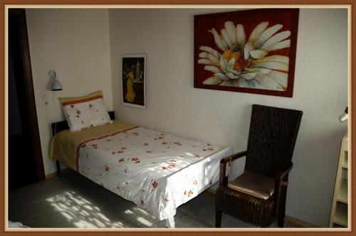 a bedroom with a bed and a chair and a painting at Panoramablick 85 m2 5 persoons in Lennestadt