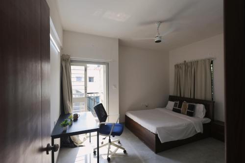 a bedroom with a bed and a desk and a window at Zenia IT Rooms in Pune