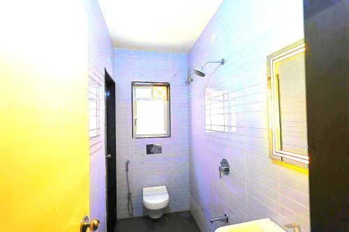 a blue bathroom with a toilet and a window at Zenia IT Rooms in Pune