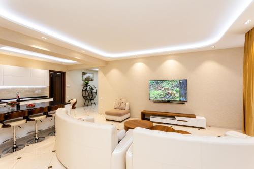 a living room with white furniture and a flat screen tv at Cityscape Luxury Apartment in Tbilisi City