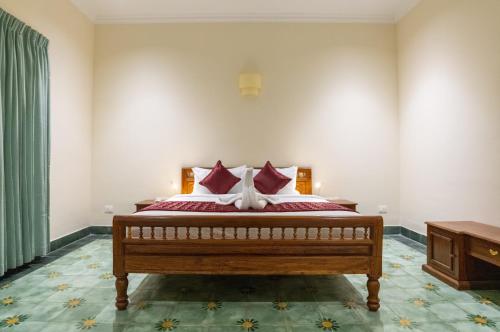 a bedroom with a bed with red and white pillows at Nadhima Villas in Kumbakonam