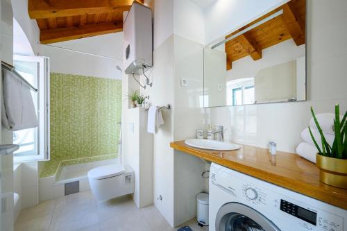 a bathroom with a sink and a washing machine at Apartments Festum in Šibenik