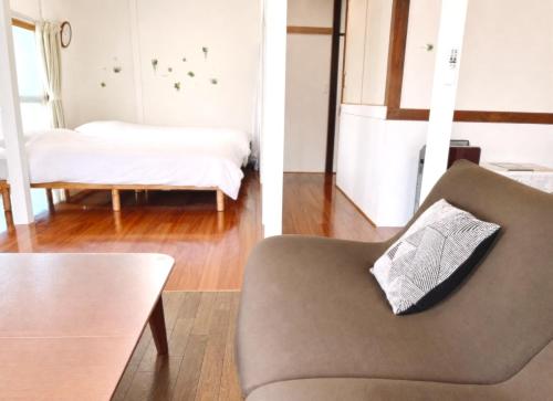 two views of a living room with a couch and a bed at かぐら庵 in Kitakata