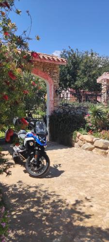 a blue motorcycle parked in front of an arch at Hotel La Corte Rosada in Villasimius
