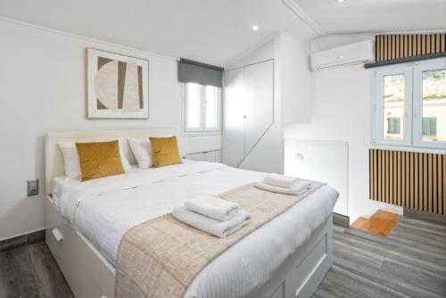 a white bedroom with a large bed with towels on it at The Loft by Life Homes in Corfu