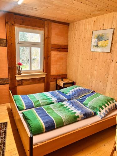 a bed in a room with wooden walls and a window at Wippertaler Hütte in Kleinfurra