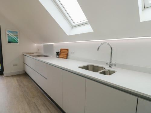 a white kitchen with a sink and a skylight at Glynllifon 7 in Llanallgo