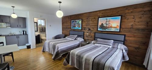 two beds in a room with a kitchen and a kitchen at Le Pirate Motel et Camping in Cap-Chat