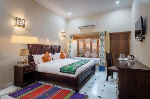 a bedroom with a bed and a desk and a television at Golden Celestial haveli jaisalmer in Jaisalmer