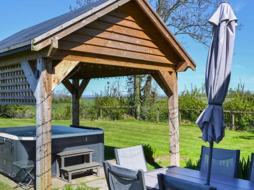 a wooden pavilion with a grill and an umbrella at Angerton Cottage in Carlisle