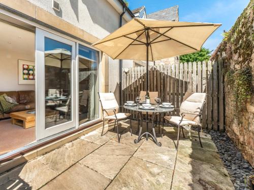 a table and chairs with an umbrella on a patio at Smugglers Den in Beadnell
