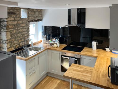 a kitchen with white cabinets and a wooden counter top at Bailey Cottage in Staindrop